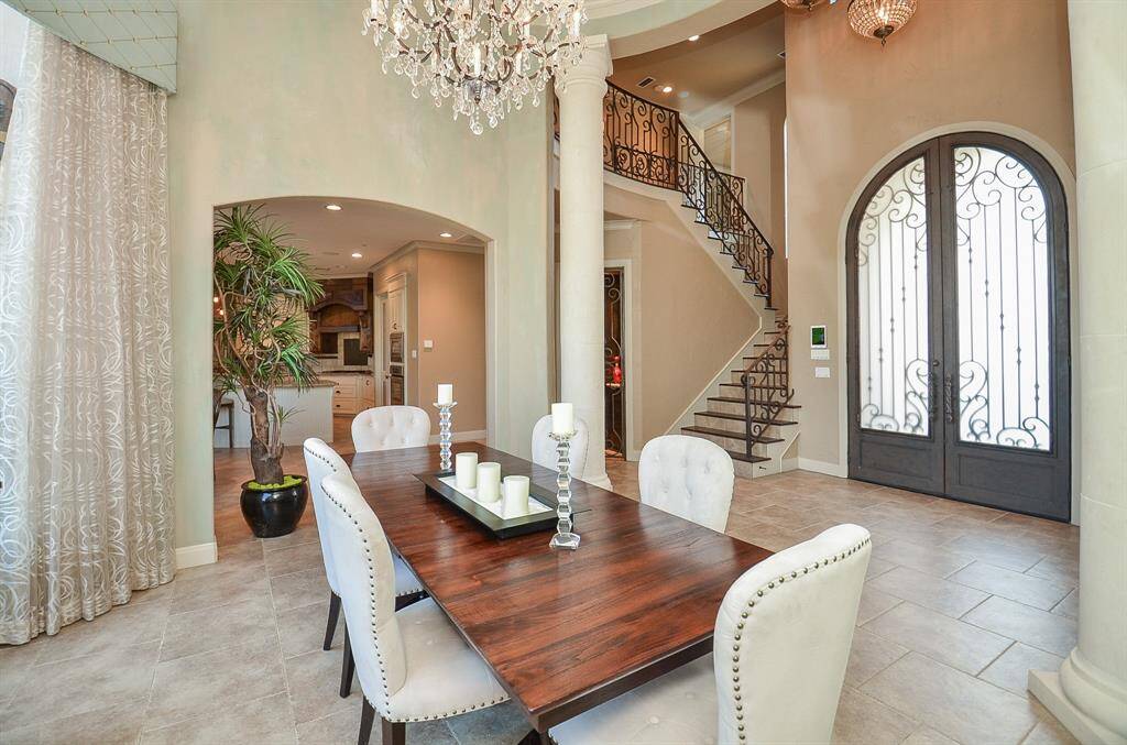 The formal dining space showcases a gracefully curved glass wall, offering enchanting views of the pool.