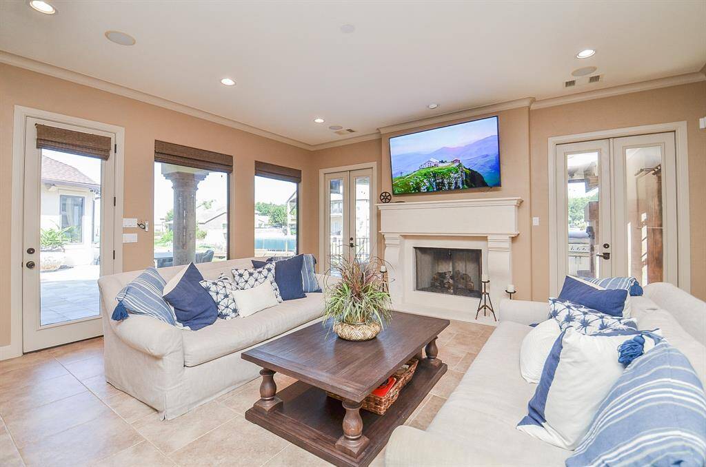This is the ground-floor living space with doors on both sides of the fireplace, leading to the summer kitchen, and another door on the left that opens to the pool deck.