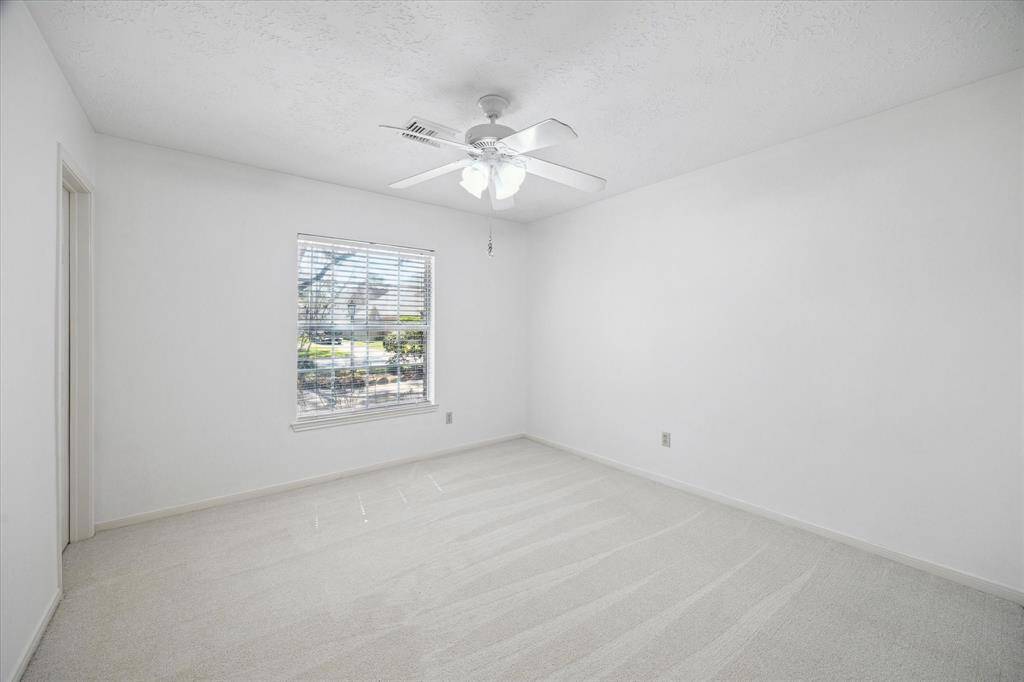 The spacious living room features high, angled ceiling, wood-look tile flooring, a brick fireplace, and custom built-in shelves, offering a cozy yet modern vibe.