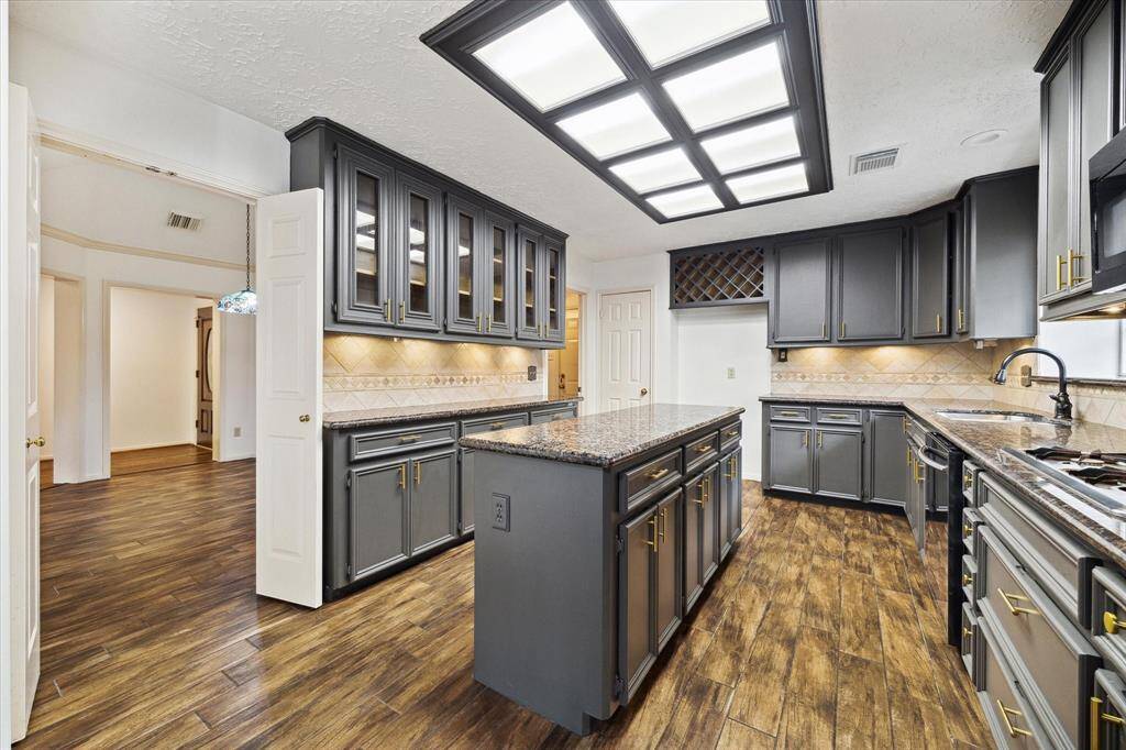 The flex room features rich hardwood floors, a lighted ceiling fan, recessed lighting and ample natural light from a large window. It opens into the primary bedroom through double doors, offering lots of potential for versatile use.
