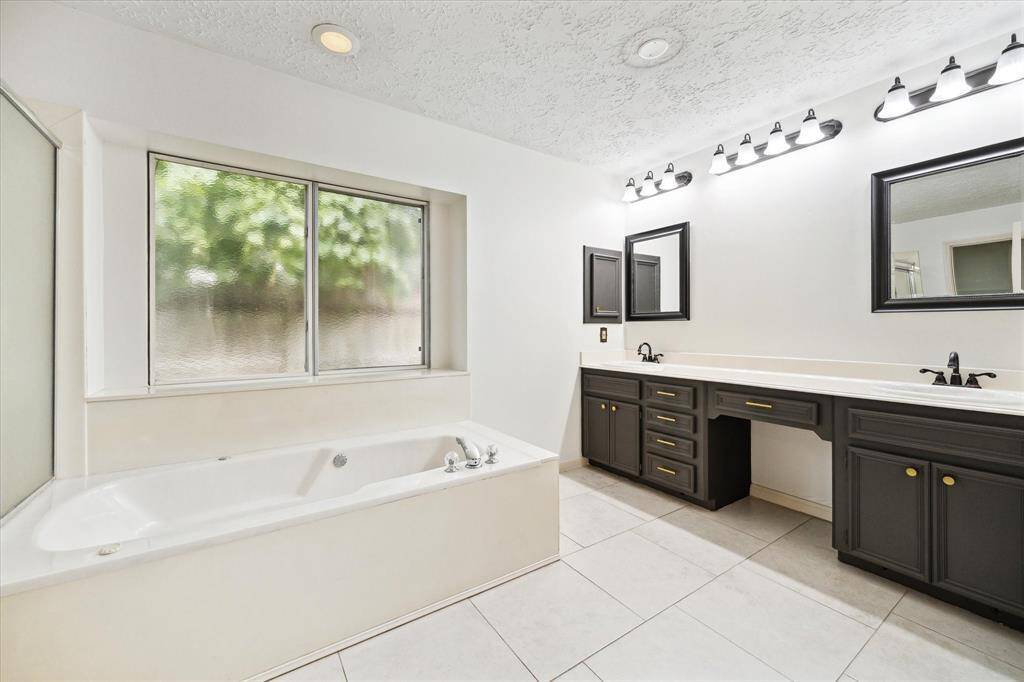 The spacious laundry room features ample cabinetry for storage, a ceiling fan, and an exterior door leading to the garage. The space is bright and functional with wood-look tile flooring. Washer and dryer is included.