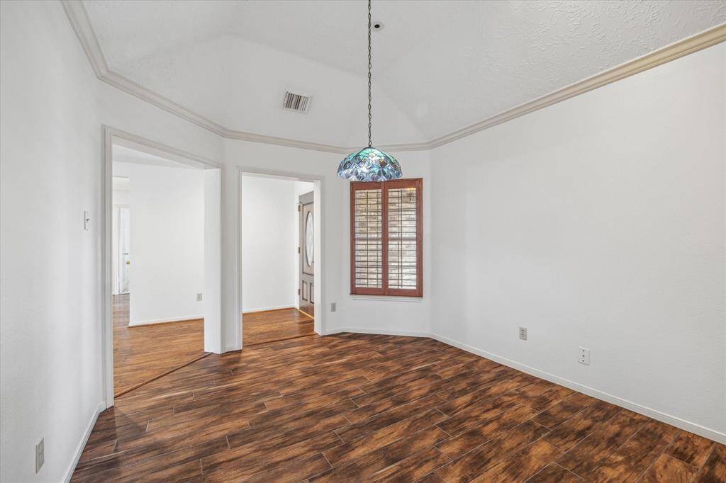 Modern kitchen with freshley painted cabinetry, granite countertops, and a central island. Features include a tile backsplash, under-cabinet lighting, and wood-look tile flooring. The room is well-lit with recessed lighting above.