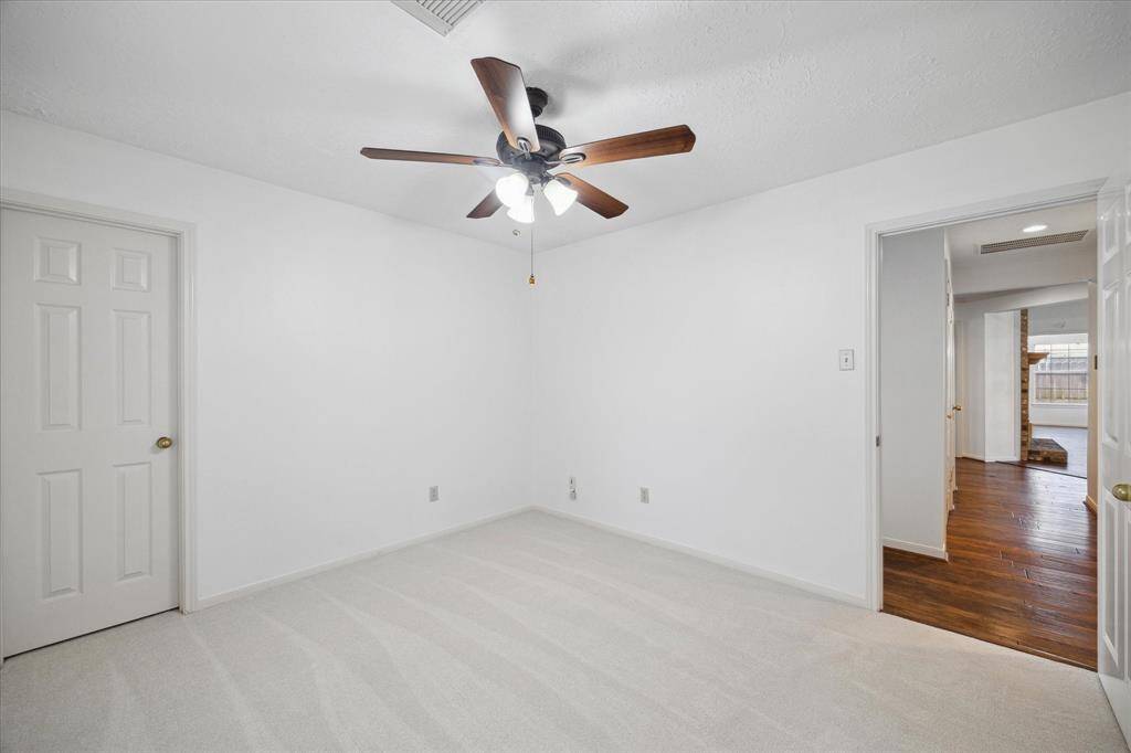 This spacious living area features a high vaulted ceiling, a cozy brick fireplace, and large windows that let in plenty of natural light. The open layout is complemented by beautiful wood look tile flooring and custom built-in shelves, providing a warm and inviting space for relaxation or entertaining.