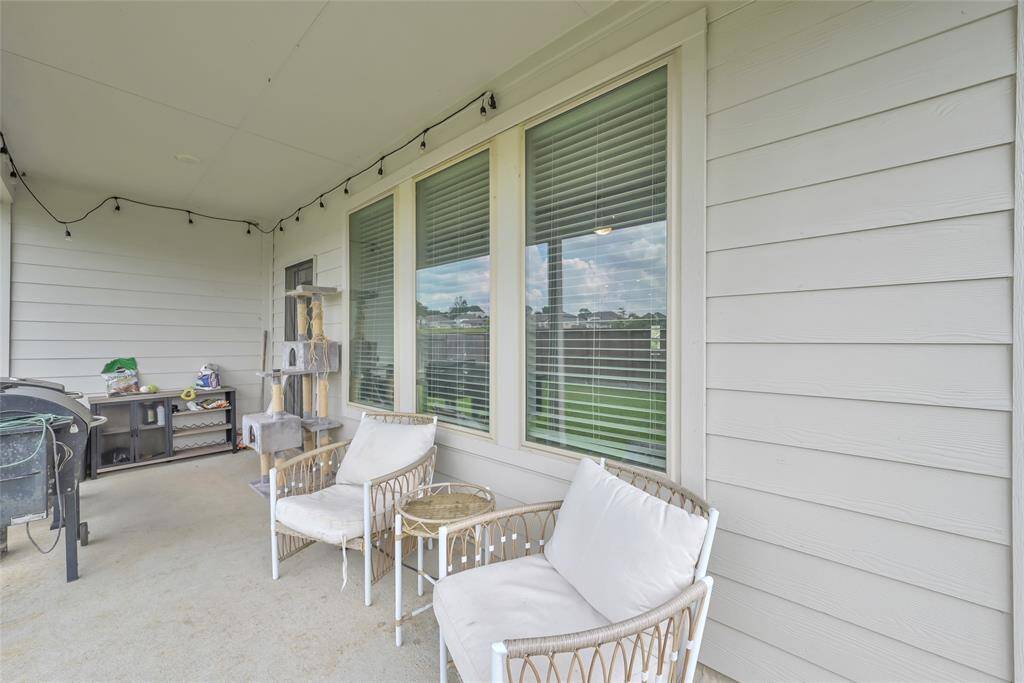 The photo shows a covered outdoor patio area with comfortable seating, a grill, and a serene view, ideal for relaxation and entertainment.