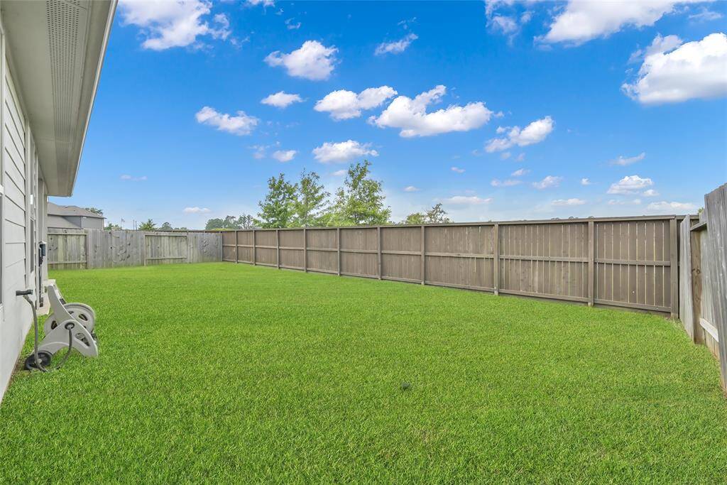 This is a spacious and well-maintained backyard with a privacy fence, lush green grass, and clear skies above, offering a great outdoor space for relaxation and activities. No back neighbors!