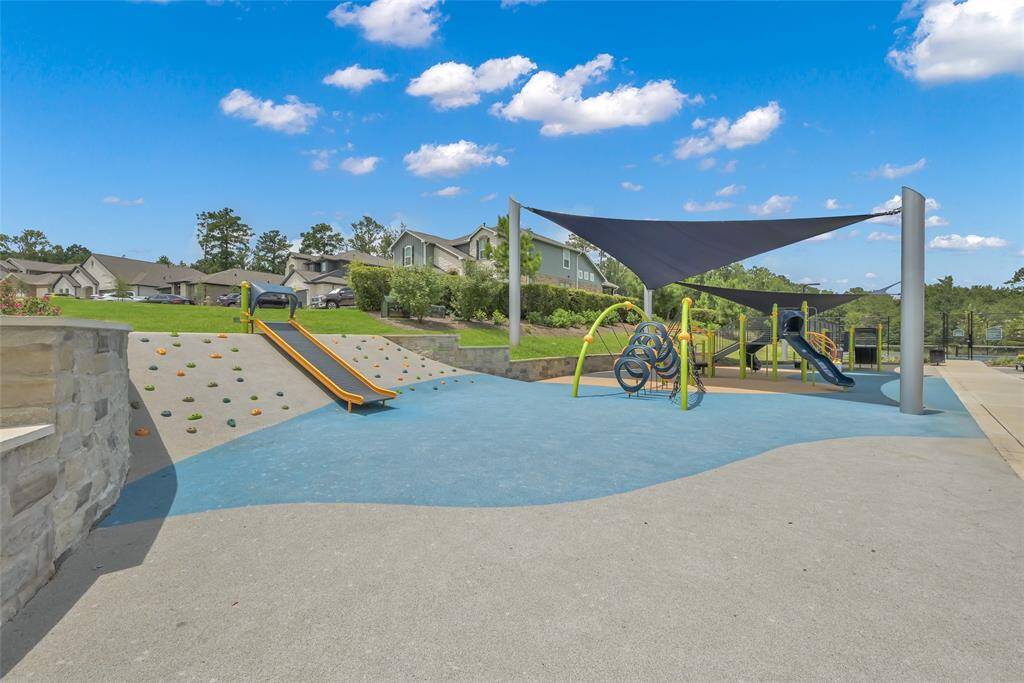 Showcasing a modern playground with climbing structures, slides, a splashpad, and shaded areas. Walking trails, restrooms, and pickleball courts as well.