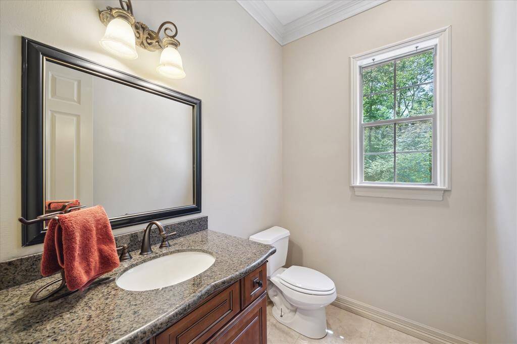 This spacious half bathroom impresses with its granite countertops, elegant fixtures, and ample room for guests.