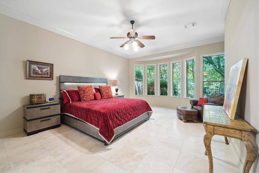 The generously sized primary bedroom is a serene retreat, featuring travertine floors and a stunning wall of floor-to-ceiling windows.