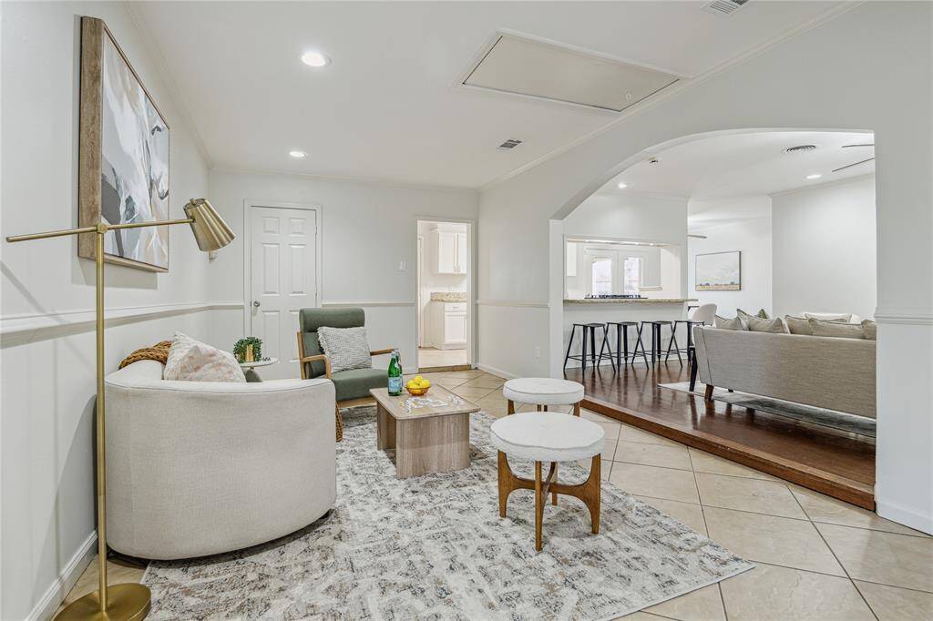 This inviting den showcases an open layout with recessed lighting and a stylish arched entryway that connects seamlessly to the secondary living space.