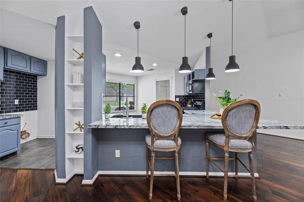 This kitchen features stylish painted cabinetry, sleek appliances and a modern subway black tile backsplash. It includes pendant lighting, ample counter space and a cozy layout perfect for cooking and entertaining.