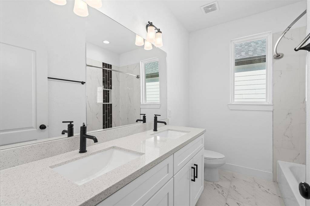The secondary bathroom is an extension of the primary! Dual vanity sinks, beautiful tiling throughout, and quartz countertops will make your guests feel right at home when getting ready.