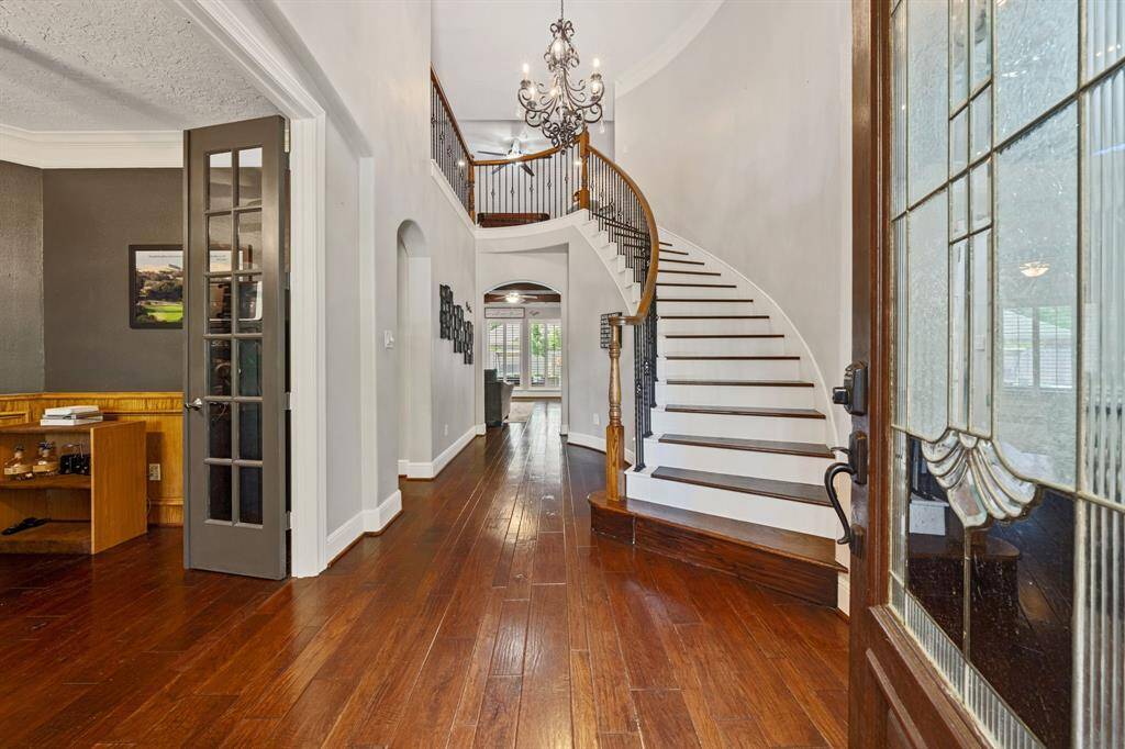 Welcoming front entryway with high ceilings, elegant chandelier and wrapped staircase.