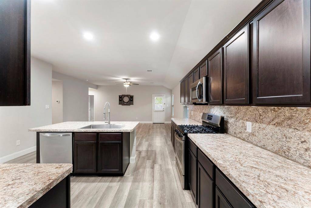 This modern kitchen features dark wood cabinets, and stainless steel appliances.