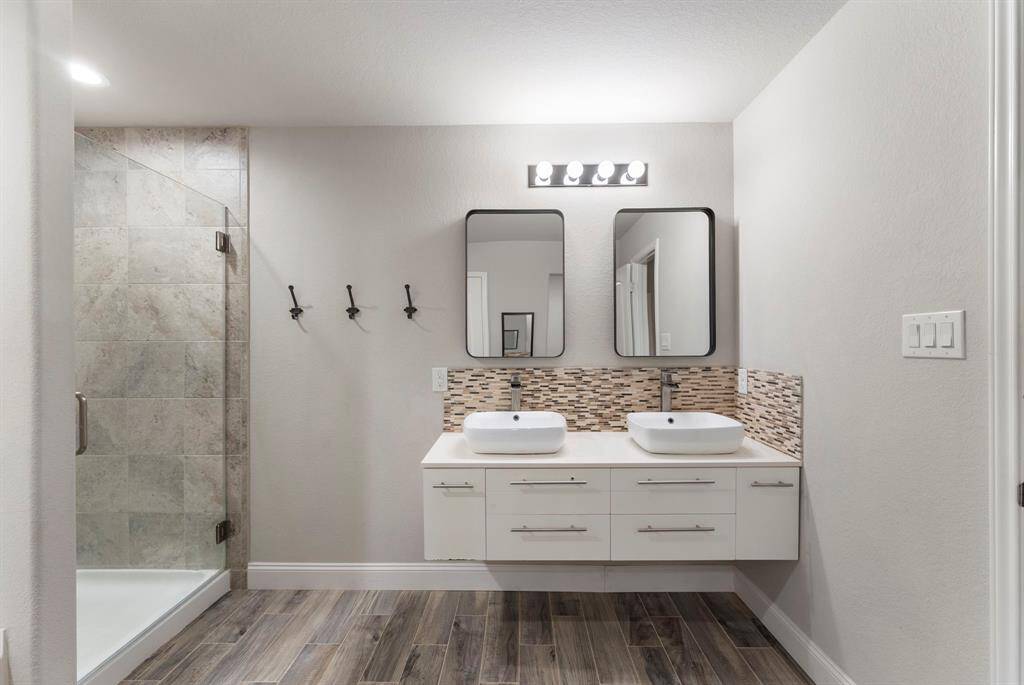 A floating double vanity with vessel sinks, and contemporary mirrors. Accented with a mosaic backsplash.
