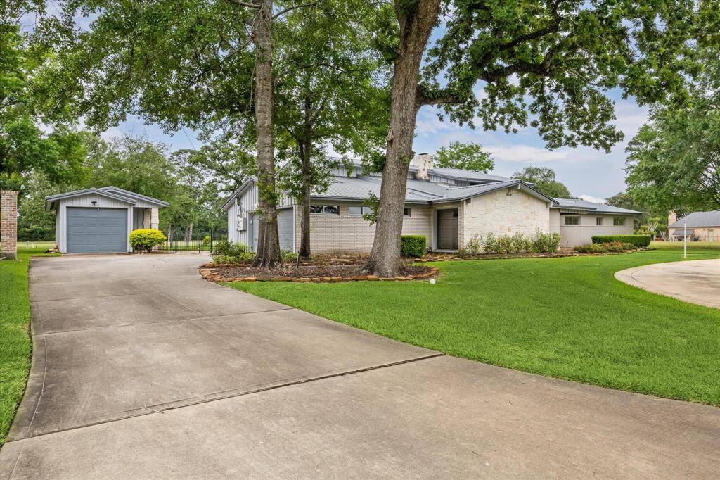 Ranch style home with stone and brick facade on large lot backing onto Champions Golf Course. Circular driveway in front with another driveway to the left to the garage and golf cart garage.