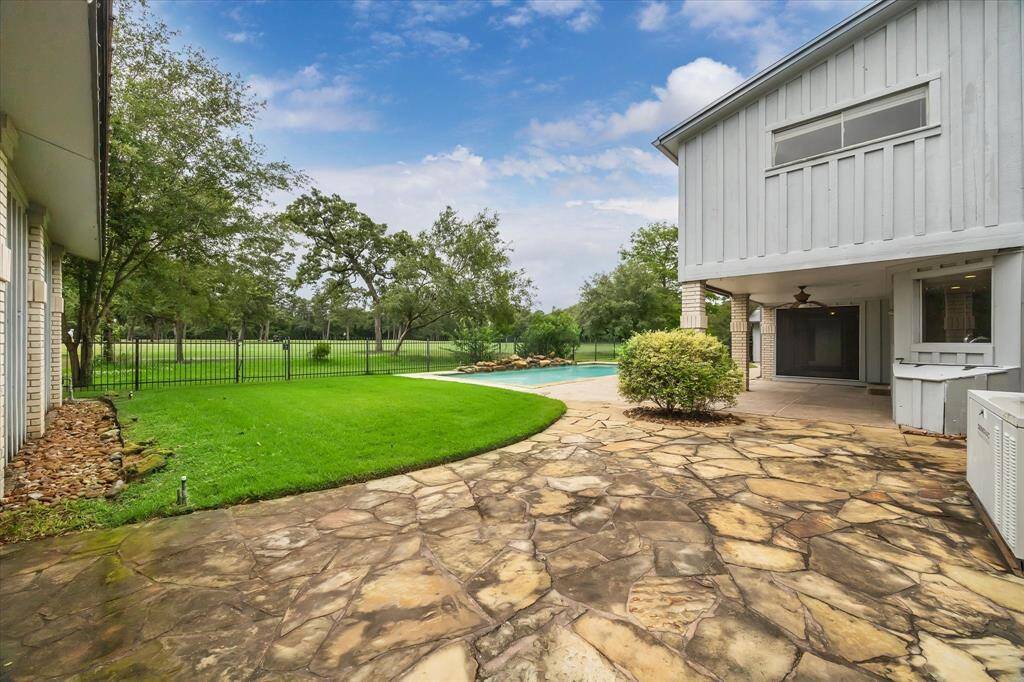 View from driveway into the backyard and patio looking toward golf course.  Note golf cart garage to the left.