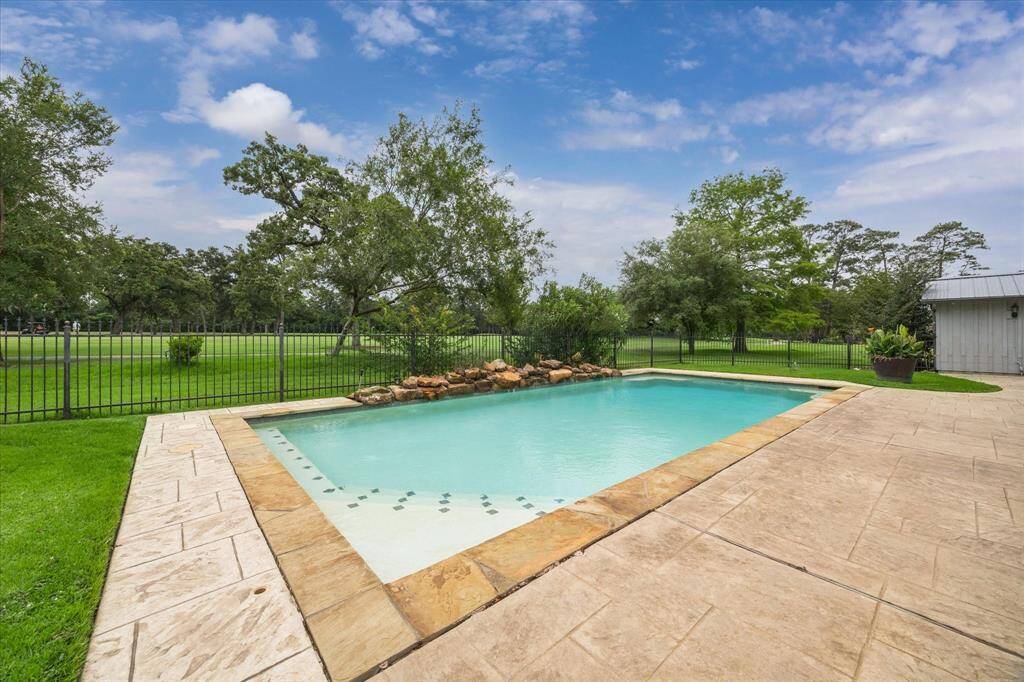 Spacious pool with rock formation fountain overlooking golf course.