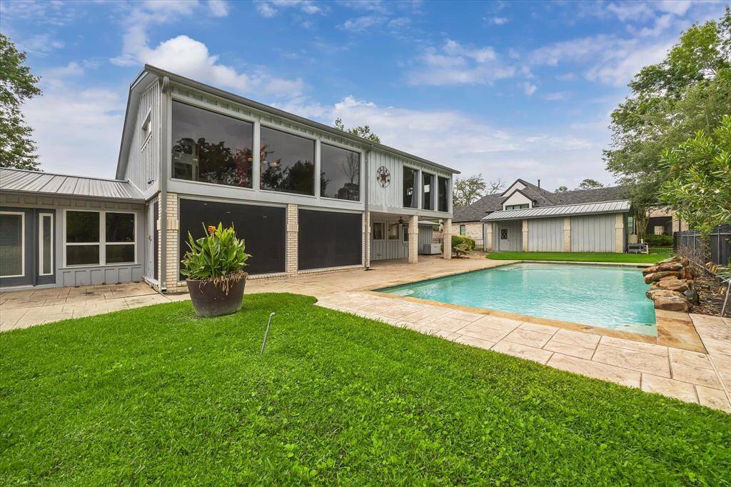 View from golf course of back of house showing pool, patio and large windows.