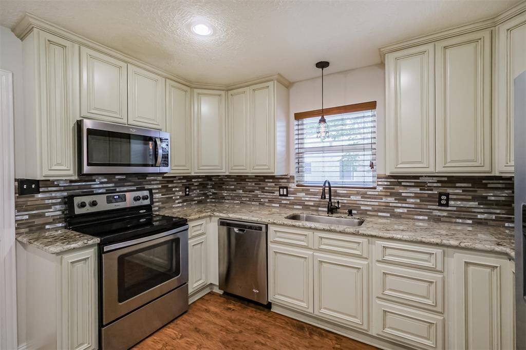 Kitchen is complete with stainless steel appliances, modern back splash and painted cabinetry.