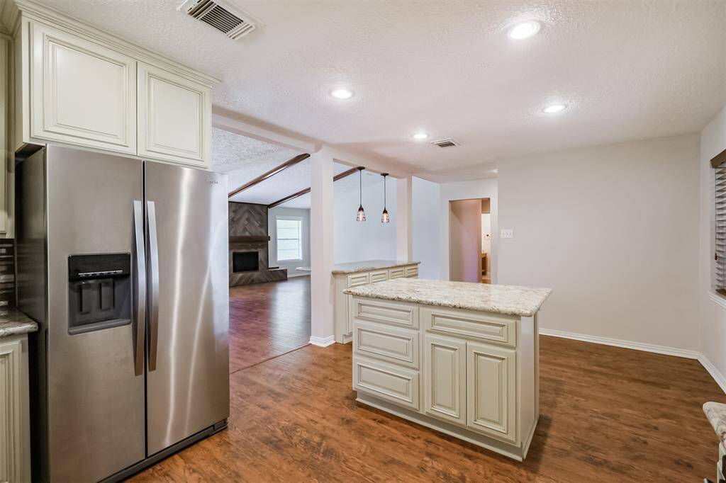 Behind the island is a quaint eat in kitchen area. Notice the stainless steel refrigerator that stays with the home.