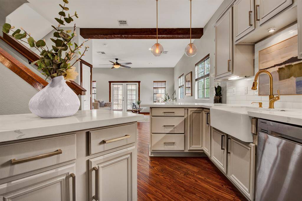 The kitchen opens gracefully to the main living space, framed by a breakfast bar, pendant lights, and rich wood trim details.