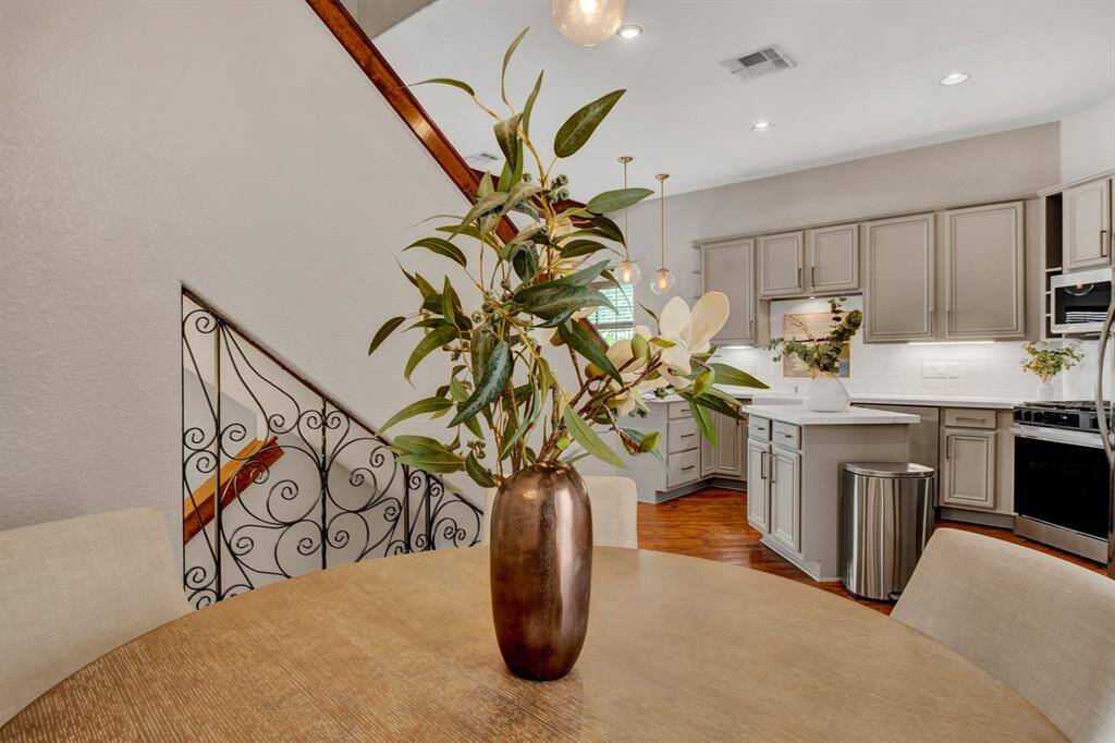 This stylish dining nook is framed by an iron staircase railing and sightlines to the kitchen, bringing together warmth, elegance, and everyday comfort.