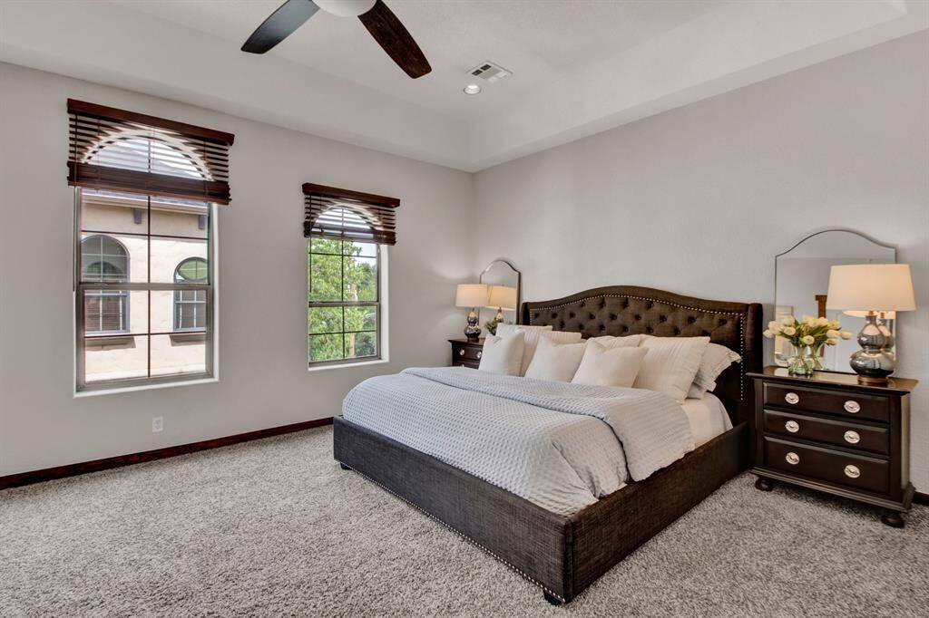 The primary suite features soaring ceilings, three oversized windows, and room for a king-size bed with additional seating or dressers.
