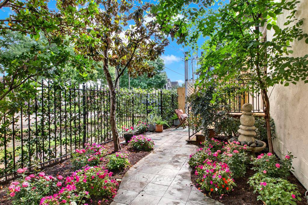 The lush, flower-lined path leads through the gated courtyard, offering a tranquil outdoor space perfect for morning coffee or evening relaxation.