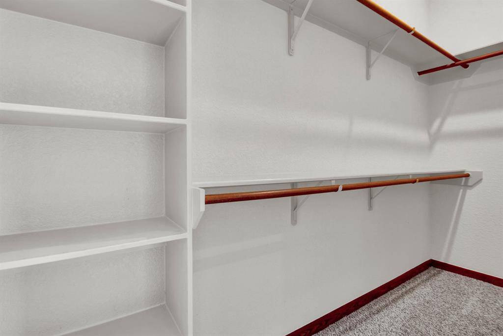 The spacious walk-in closet includes built-in shelving and dual hanging rods, offering ample space for organized storage.