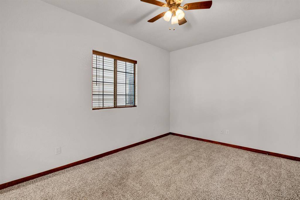 The ground level includes a versatile spacious room with neutral tones, a ceiling fan, and natural light, making it perfect for the flexibility of a bedroom or home office use
