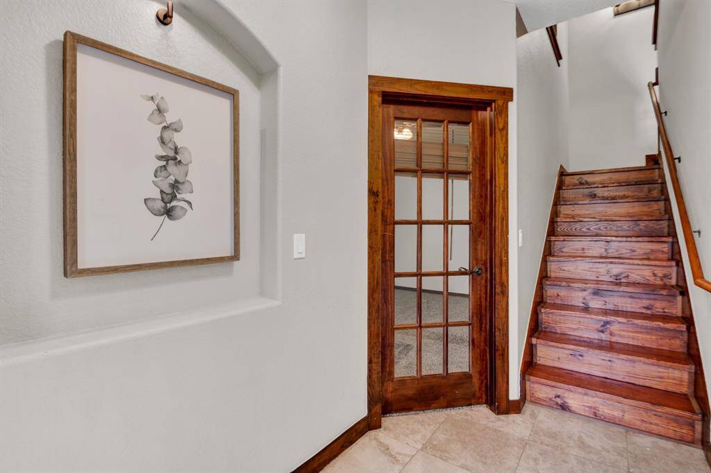 The entryway showcases a warm wood door with decorative ironwork and a cozy alcove with accent lighting