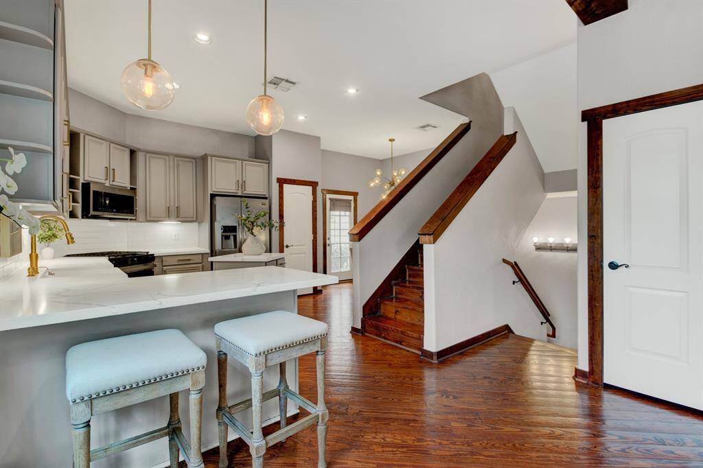 Bright and stylish, the open-concept kitchen features sleek quartz counters, custom cabinetry, and pendant lighting, flowing seamlessly into the living space with rich hardwood floors.