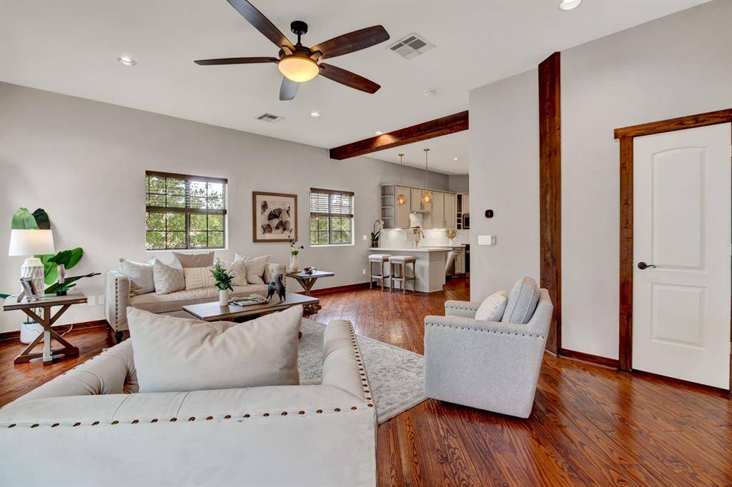 The open layout seamlessly connects the living room to the kitchen, showcasing exposed wood beams and effortless flow for everyday living or hosting guests.