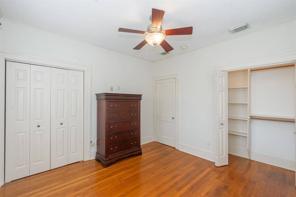 The third bedroom features hardwood floors, a ceiling fan, and ample storage with a double-door closet and built-in shelving. The light walls enhance the spacious feel.