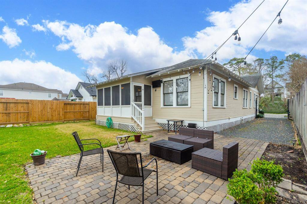 A spacious backyard with a patio area perfect for outdoor entertaining. It includes comfortable seating, string lights for ambiance.