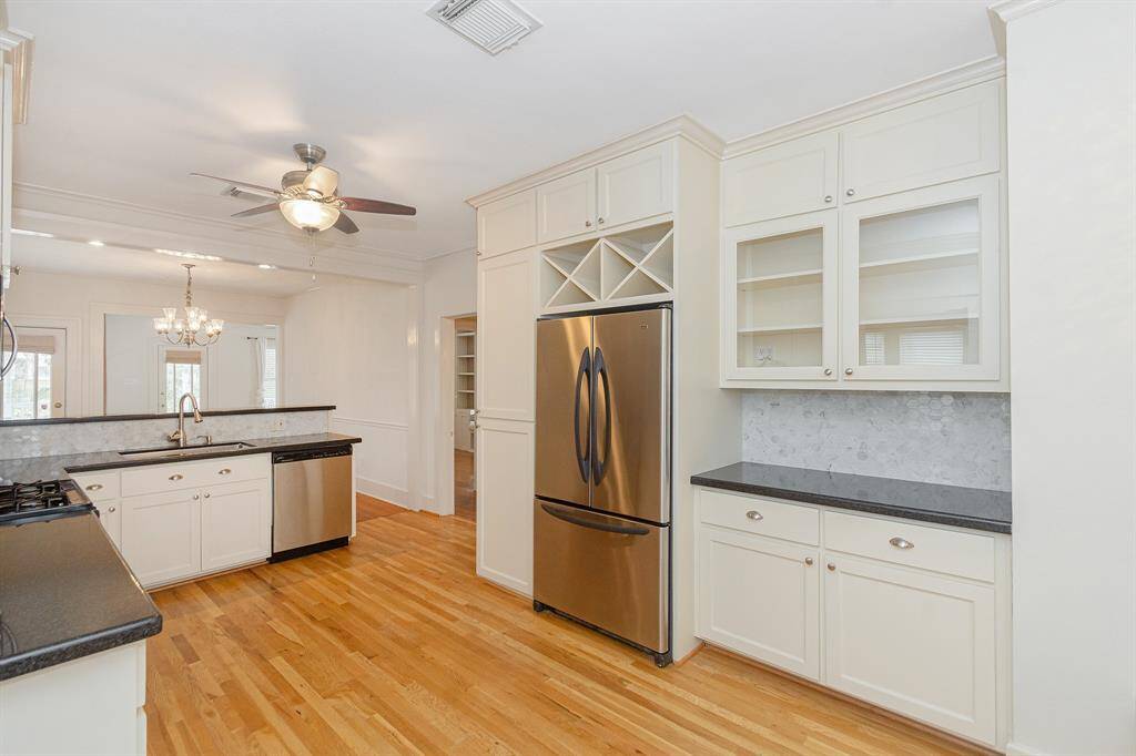The kitchen features a pantry with pull-out shelves, a stylish dry bar, a built-in wine rack, and elegant glass-paneled cabinetry.