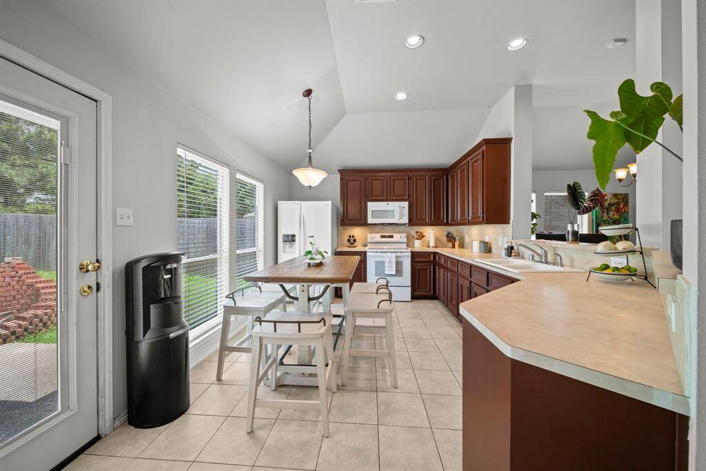 Bright kitchen with rich cabinetry, ample counter space, and a cozy dining area overlooking the backyard.