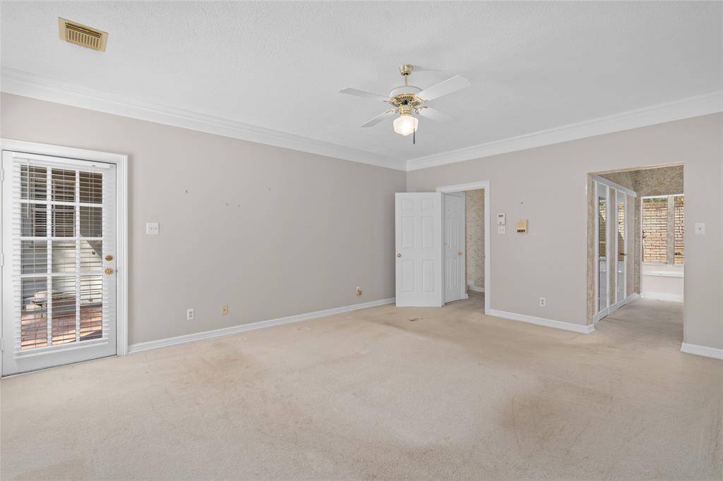 Another view of your primary bedroom focuses on the French doors leading to the patio and hallway into the primary bath.