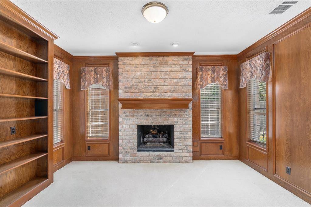 This versatile room off the primary bedroom features a brick fireplace, built-in wood shelving, and large windows and can be used as a home office, sitting room or whatever you can imagine.
