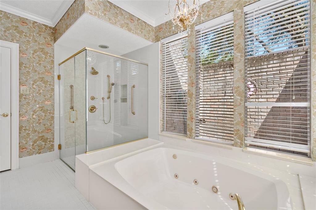 Relax in your luxurious soaking tub after a long day. The spacious glass-enclosed shower with gold fixtures has two grab bars for safety. The large windows provide ample natural light while the chandelier adds a touch of class.