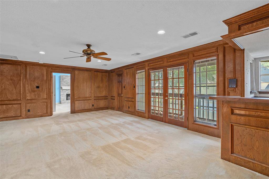 The large upstairs game room features warm wood paneling, a ceiling fan and large windows with French doors opening to a balcony. A walk-in cedar closet is an additional benefit offered here. It's perfect for a entertainment space with plenty of natural light.