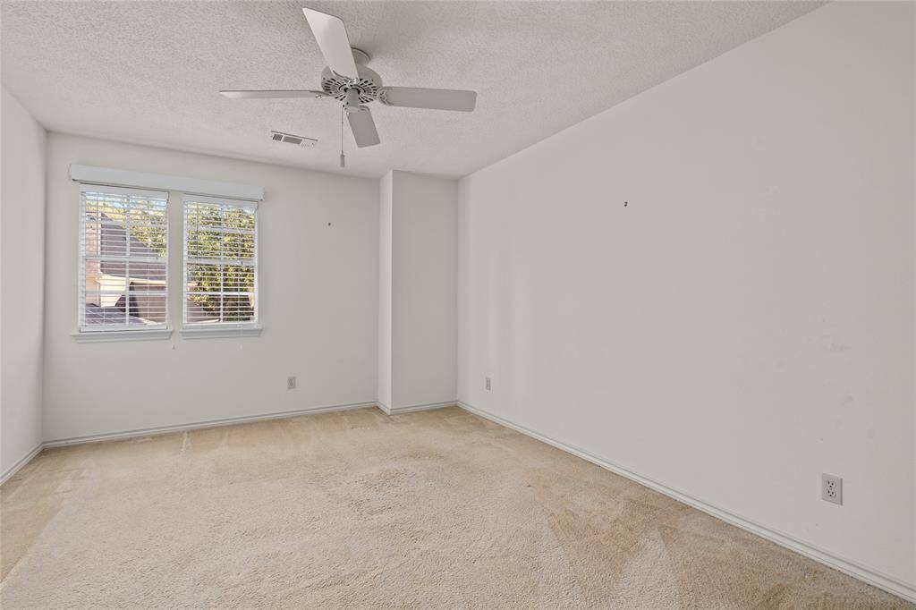 Another upstairs bedroom with  neutral walls and carpet, a ceiling fan, and a window offering a bright and airy atmosphere perfect for personalization.