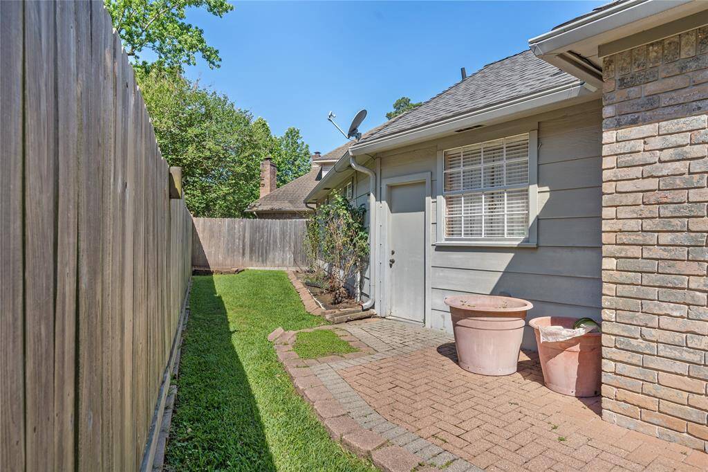 Your side yard has a wooden privacy fence, rose garden and a brick pathway. There's a small grassy area and exterior wall with a door and window making this space cozy and low-maintenance.