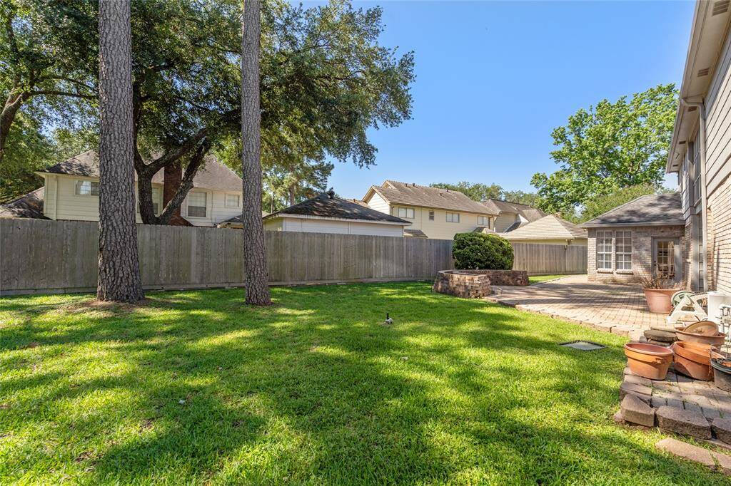 This is a view of your shady backyard with mature trees and a wooden fence for privacy. There is a small raised garden bed.