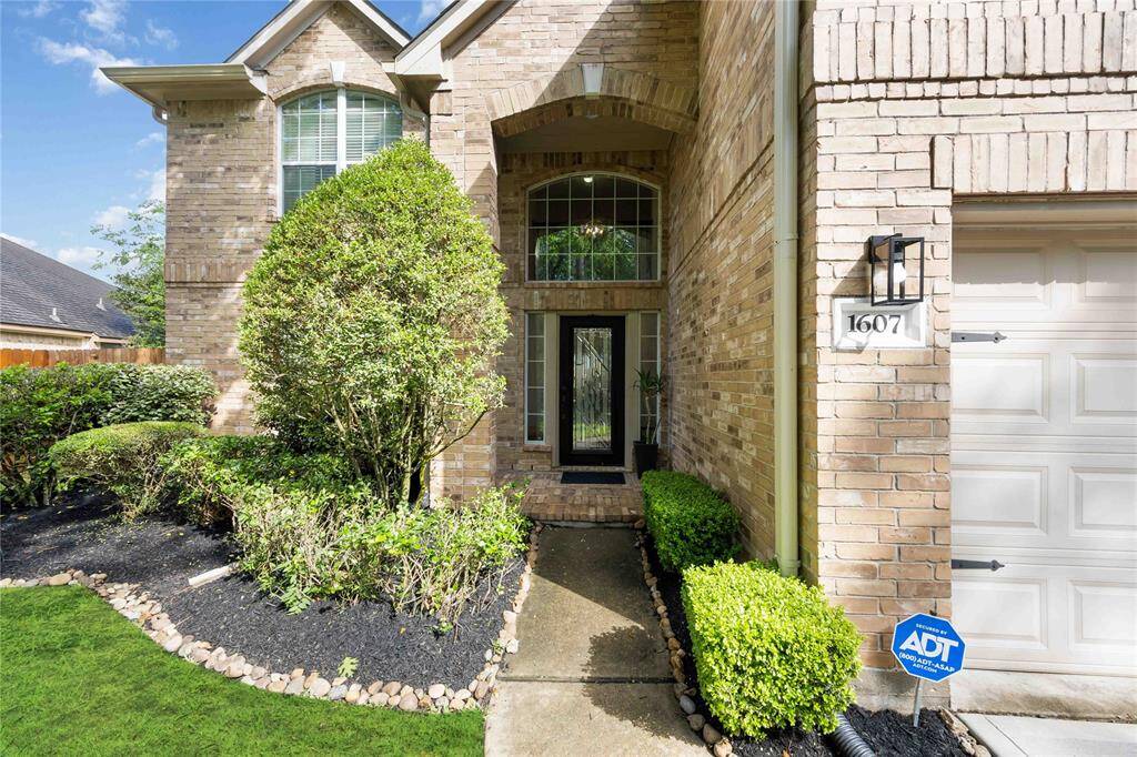 A welcoming entryway, featuring manicured shrubs and a well-maintained path leading to a modern front door.