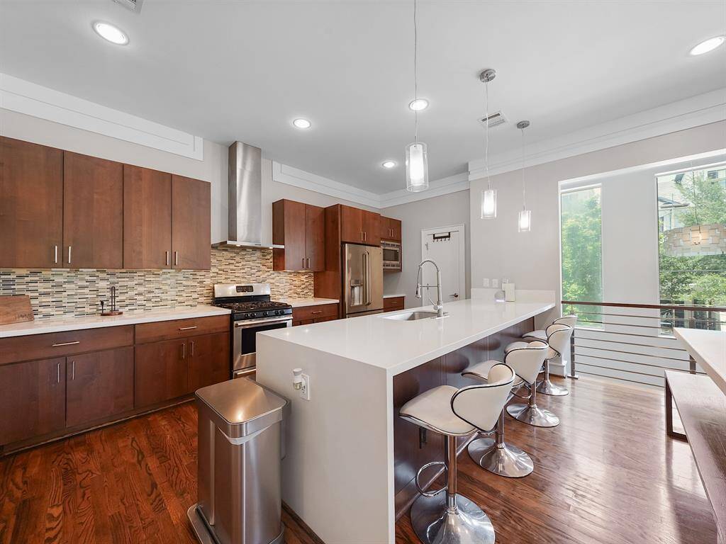 Prepare to be captivated by this home's striking contemporary kitchen, a true culinary masterpiece. Imagine creating gourmet meals amidst sleek Silestone countertops, perfectly balanced by the warmth of custom cabinetry and the shimmering allure of a glass tile backsplash.
