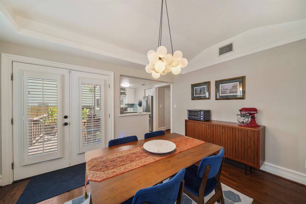 This dining area features a modern light fixture, double doors leading to a deck, and a view into the kitchen. It has a cozy, inviting atmosphere.