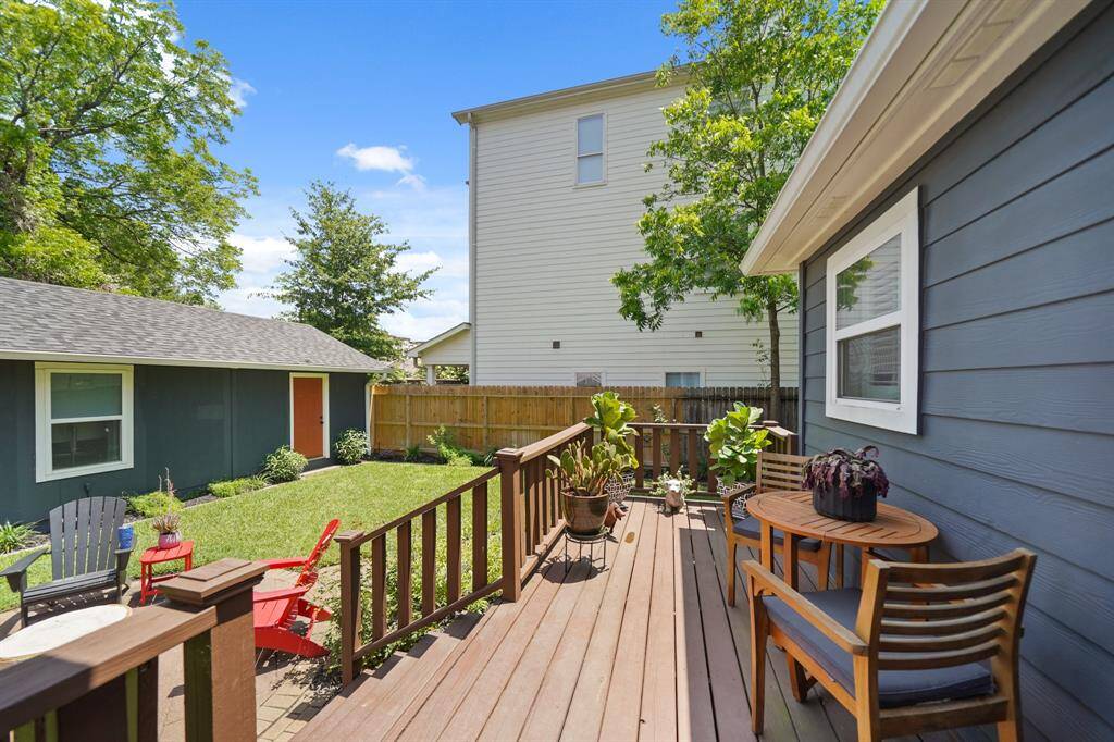 This photo features a cozy backyard with a wooden deck, perfect for relaxing. The yard is fenced, ensuring privacy, and includes a small outbuilding. Ideal for outdoor enjoyment.
