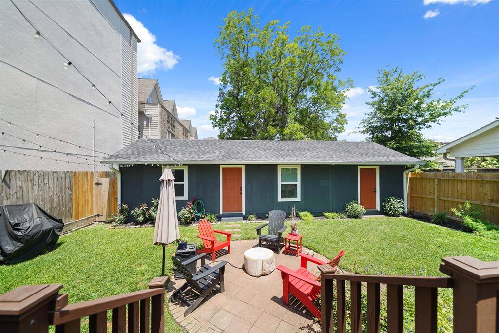 Charming backyard with a well-maintained lawn, cozy seating area, and fire pit perfect for outdoor gatherings. The space is enclosed by a wooden fence for privacy and features a guest house that can double as a home office, or rental space for additional income.