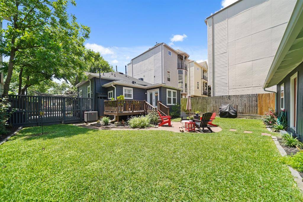 This backyard offers a spacious, well-maintained lawn with a cozy patio area, perfect for entertaining. The area is enclosed by a wooden fence, providing privacy, and features mature trees for shade.